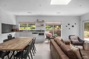 a kitchen and living room with a table and a couch at Grovebrook Cottage, Broughton in Woodhill