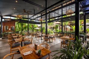 a restaurant with wooden tables and chairs and plants at Kahayana Suites Ubud in Ubud