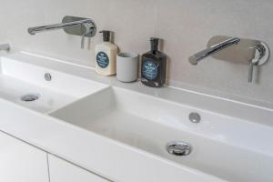 a white bathroom sink with two bottles of soap at Grovebrook Cottage, Broughton in Woodhill +25 photos
