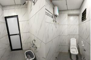 a white bathroom with a toilet and a sink at Hotel Rudra in Wākal