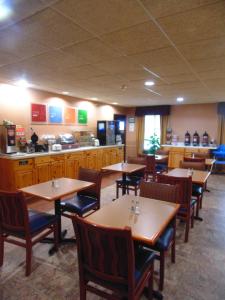 a restaurant with wooden tables and chairs and a counter at American Inn and Suites Houghton Lake in Houghton Lake