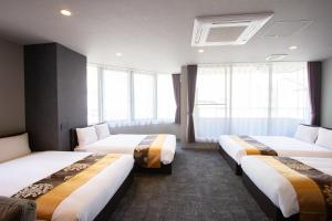 three beds in a hotel room with windows at Hotel FUK O in Fukuoka
