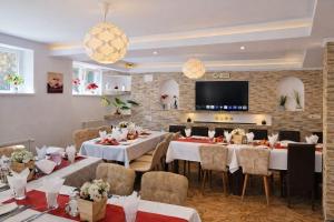 a restaurant with tables and chairs and a flat screen tv at Pensiunea Clasic in Buşteni