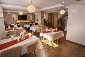 a restaurant with white tables and chairs in a room at Pensiunea Clasic in Buşteni