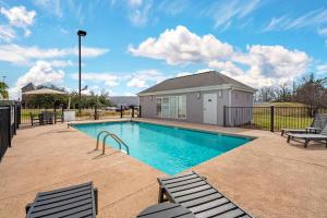 a swimming pool with two chairs and a house at Comfort Inn West Monroe near Sports & Events Center in West Monroe