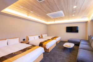 a hotel room with two beds and a couch at Hotel FUK O in Fukuoka