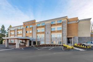 a hotel building with a car parked in a parking lot at Comfort Inn & Suites Tigard near Washington Square in Tigard