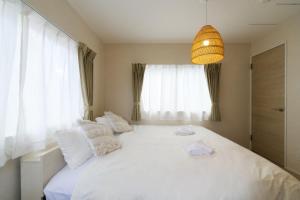 a bedroom with a large white bed with white pillows at JAPANDI HOTEL Nagoya in Chikusachō