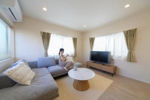 a woman sitting on a couch in a living room at JAPANDI HOTEL Nagoya in Chikusachō