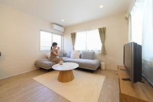 a woman sitting on a couch in a living room at JAPANDI HOTEL Nagoya in Chikusachō