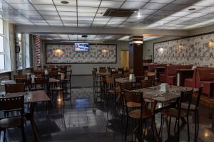 a dining room with tables and chairs and a screen at Olympica Hotel in Almaty