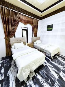 two beds in a room with white walls at Bints Guesthouse Syariah in Banjarbaru