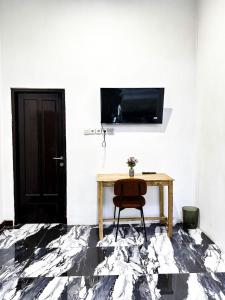 a room with a table and a television on a wall at Bints Guesthouse Syariah in Banjarbaru