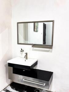 a white bathroom with a sink and a mirror at Bints Guesthouse Syariah in Banjarbaru +14 photos