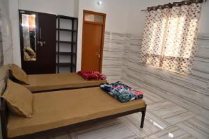 two beds sitting in a room with a window at Sarvjanik Hindu Dharamshala in Nīmri