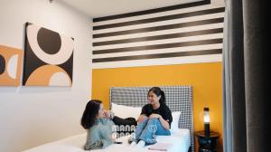 two women sitting on a bed in a room at Stallionz by MyKey in Ipoh