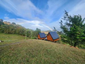 a barn on a hill with a rainbow in the background at Brisas De Los Santos Lodge 1 in Sierra