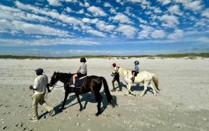 a group of people riding horses on the beach at The Dunes in Yzerfontein