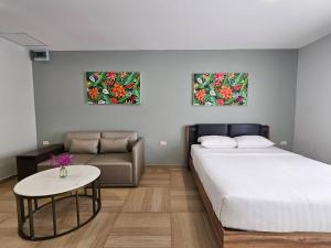 a bedroom with a bed and a couch and two paintings at Chiva Bangkok Hotel in Bangkok