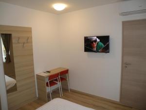 a room with a bed and a table and a monitor on the wall at Postojna Rooms in Postojna