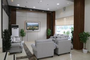a living room with couches and a tv on a wall at Almawasem Alarbaa for Serviced Apartments - Standard in Al Jubail
