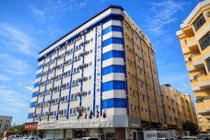 a tall white building with blue windows at Almawasem Alarbaa for Serviced Apartments - Standard in Al Jubail