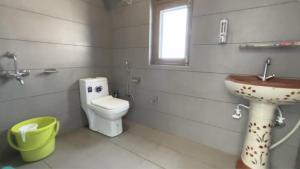 a bathroom with a sink and a toilet and a window at Kinara by The Ashram in Bīr