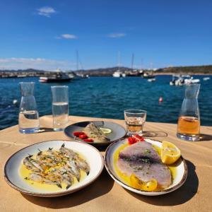 two plates of food on a table near the water at Angeliki Seaside Hotel in Aliki +23 photos