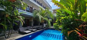 a courtyard with a swimming pool and palm trees at Jepun Segara Guest House in Kuta