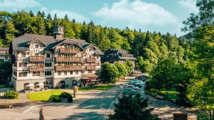 a large building on a street with trees at Hotel Savoy Špindlerův Mlýn in Špindlerův Mlýn
