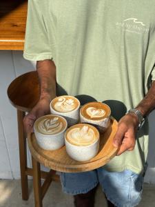 a man holding a tray with four cups of coffee at Surf Lodge Madiha in Matara +80 photos