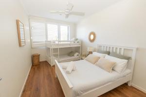 a white bedroom with a bed and a window at Saltwater 5 - sleeps 8 - close to Main Beach in Point Lookout
