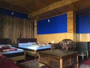 a bedroom with two beds and a couch and a table at Hotel Aditya in Aritar