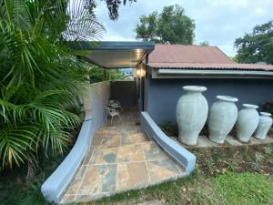 a patio with three large white vases on the side of a house at 22 Symmonds Studio in Melmoth