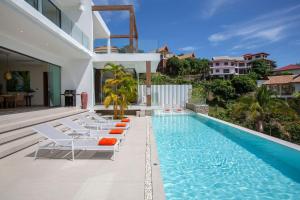 a swimming pool with lounge chairs next to a house at Luxury Sea View Jungle Beach Villa Walk to Beach in Ban Bang Po