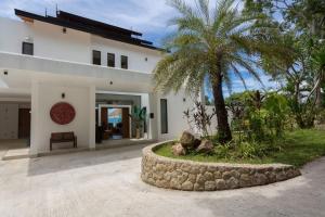a house with a palm tree in front of it at Luxury Sea View Jungle Beach Villa Walk to Beach in Ban Bang Po