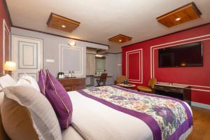 a bedroom with a large bed and a red wall at Conifer Suites & Spa Darjeeling in Darjeeling +35 photos