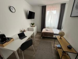 a small white room with a bed and a desk at OMNI Rooms - Oranienburg in Oranienburg