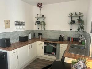 a kitchen with white cabinets and a sink at Harrys Hideaway Cottage in Haworth