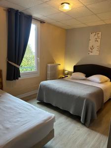 a bedroom with two beds and a window at Hôtel l'Annexe in Moux-en-Morvan