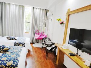 a hotel room with two beds and a television at 八零年代客栈 in Hanqiyu