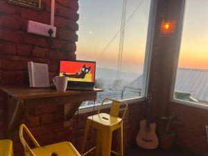 a laptop sitting on a table in front of a window at Backpacker Storey in Bīr