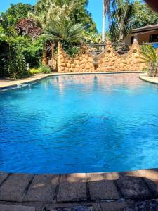 a swimming pool with blue water in front of a stone wall at 22 Symmonds Studio in Melmoth