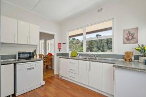 a kitchen with white cabinets and a large window at Misty Pines in Leura