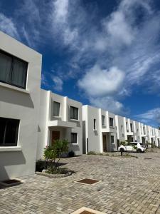 a row of white apartment buildings with a cloudy sky at North Island View Family Duplex with private pool by LOV Mauritius in Grande Gaube