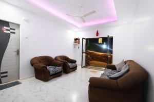 a living room with two chairs and a tv at FabHotel Sharvi in Mahabaleshwar
