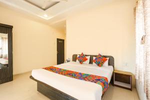 a bedroom with a large white bed with colorful pillows at FabHotel Sharvi in Mahabaleshwar