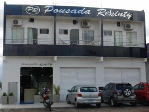 a white building with cars parked in front of it at Pousada Rekinty in Canindé de São Francisco