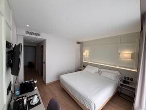 a bedroom with a white bed and a television at Playa de Foz Hotel & Spa by gaiarooms in Foz