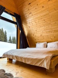 a bed in a wooden room with a window at La Știubei Cabin in Mărişel